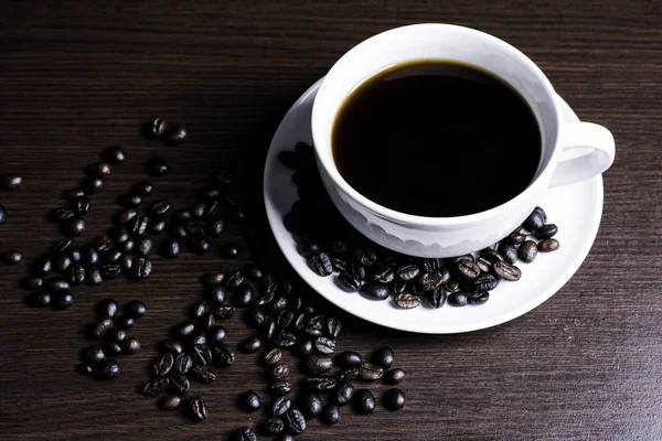 Kupası ve kahve çekirdeği ahşap arka plan üzerinde siyah kahve.