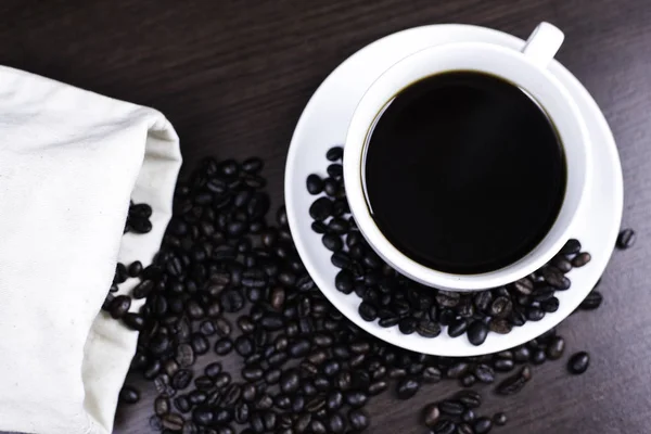 Kupası ve kahve çekirdeği ahşap arka plan üzerinde siyah kahve.
