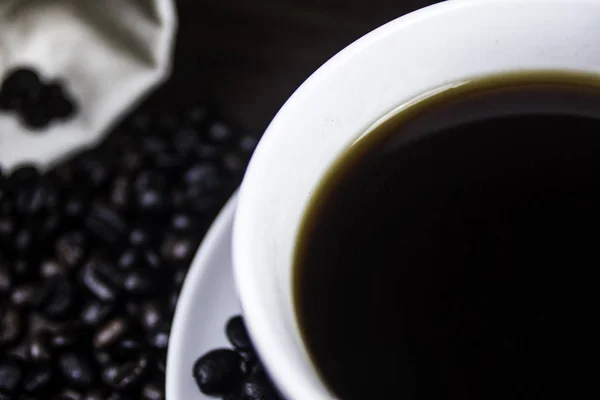 Kupası ve kahve çekirdeği ahşap arka plan üzerinde siyah kahve.