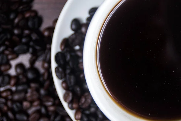 Kupası ve kahve çekirdeği ahşap arka plan üzerinde siyah kahve.