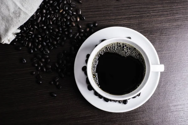 白いカップとウッドの背景にコーヒー豆のブラック コーヒー — ストック写真