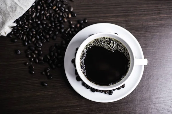 白いカップとウッドの背景にコーヒー豆のブラック コーヒー — ストック写真