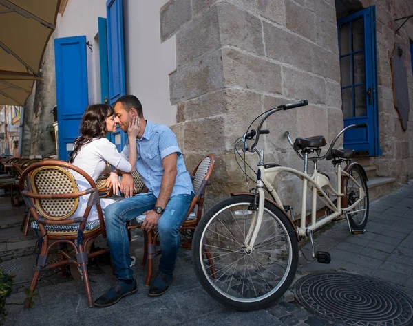 Lovely couple sitting in sidewalk cafe near their tandem bicycle — Stock Photo, Image