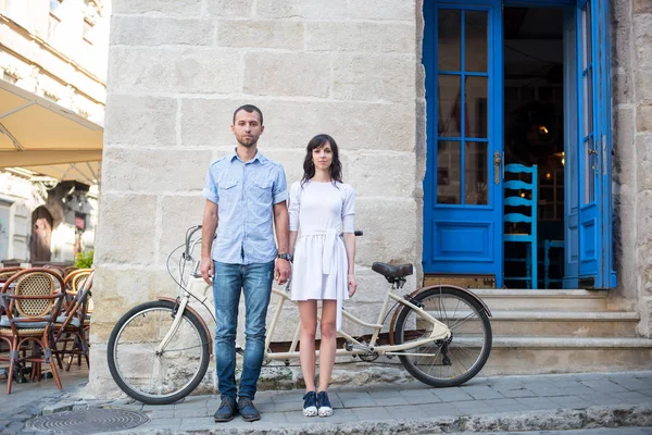 Chico y chica cerca de tándem bicicleta, paredes y puerta vintage — Foto de Stock