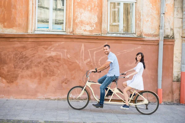 Молодая пара на тандеме на велосипеде на улице города — стоковое фото