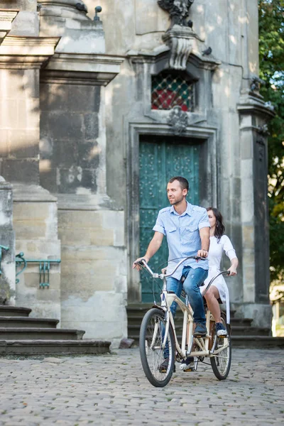 Молода пара на ретро тандемному велосипеді на вулиці міста — стокове фото