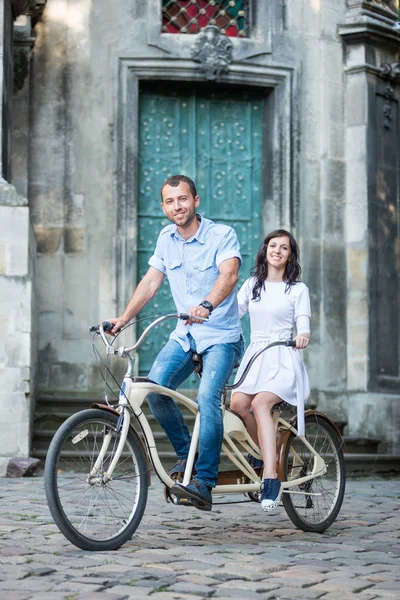 Νεαρό ζευγάρι στο ρετρό ποδήλατο παράλληλα στο δρόμο πόλης — Φωτογραφία Αρχείου