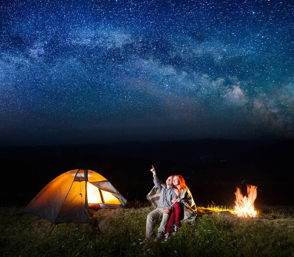 Tourist man showing red-haired woman at the stars in the sky.  