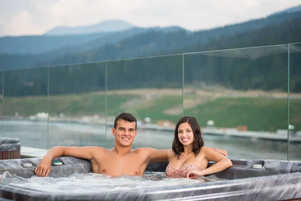 Casal jovem relaxante desfrutando jacuzzi banheira de hidromassagem — Fotografia de Stock