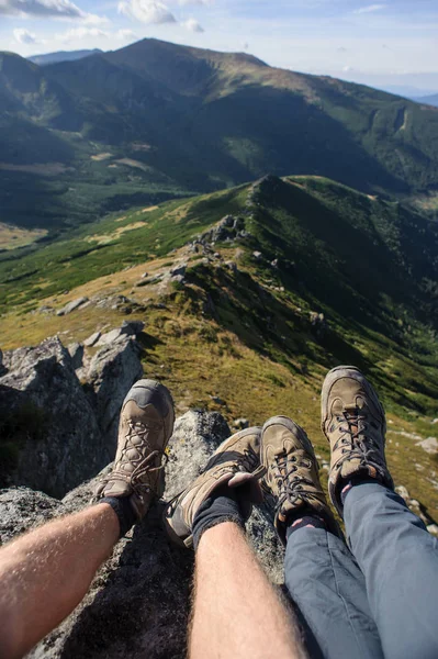 Couple\'s legs on the rock on top of the mountain