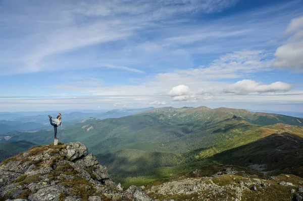 Молодая женщина практикует йогу на вершине горы — стоковое фото