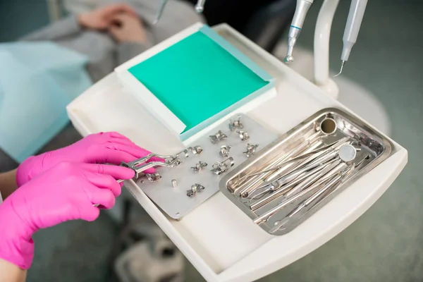 Dentista con las manos enguantadas está trabajando con el equipo dental — Foto de Stock