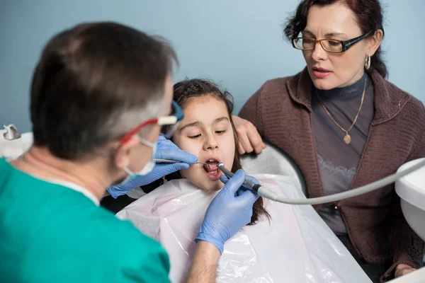 Junges Mädchen mit ihrer Mutter beim ersten Zahnarztbesuch. — Stockfoto