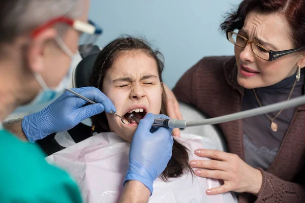 Junges Mädchen mit ihrer Mutter beim ersten Zahnarztbesuch. — Stockfoto
