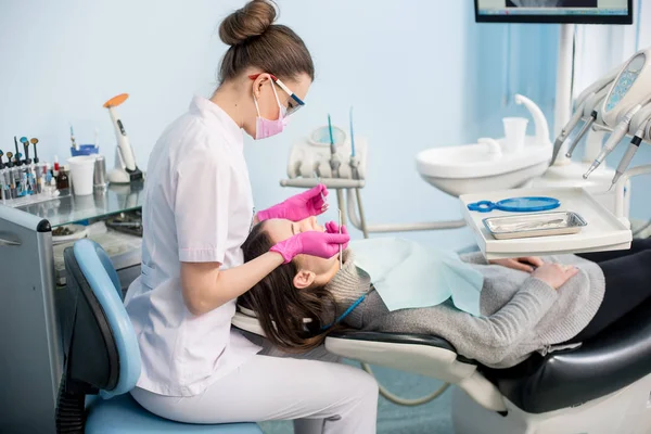 Dentiste féminine traitant les dents des patients — Photo