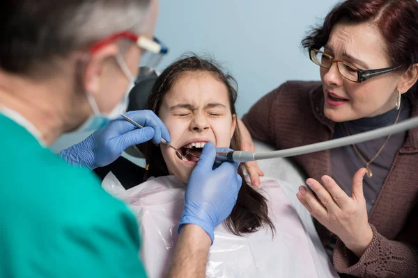 Junges Mädchen mit ihrer Mutter beim ersten Zahnarztbesuch. — Stockfoto