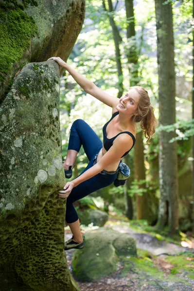 Mujer joven escalando en grandes rocas al aire libre — Foto de Stock