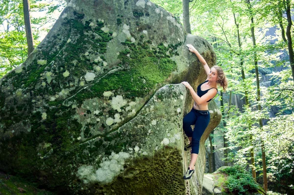 Jovem mulher escalando em grandes pedras ao ar livre — Fotografia de Stock