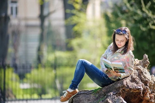 Mädchen sitzt im Park und liest ein Buch — Stockfoto