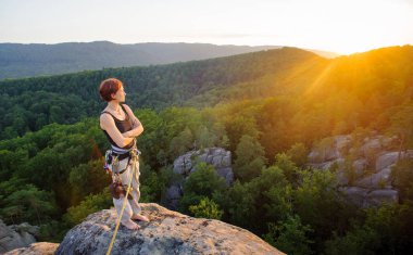 Kız tırmanışçısı yüksekte akşam üzerinde dağ tepe üzerinde