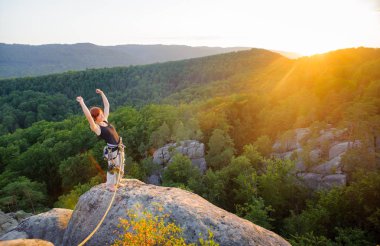 Kız tırmanışçısı yüksekte akşam üzerinde dağ tepe üzerinde