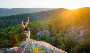 Kız tırmanışçısı yüksekte akşam üzerinde dağ tepe üzerinde