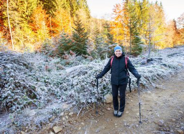 Sırt çantası ile bir dağ yolda yürüyen yaşlı kadın uzun yürüyüşe çıkan kimse