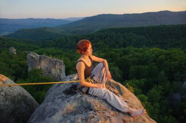 Kız tırmanışçısı yüksekte akşam üzerinde dağ tepe üzerinde
