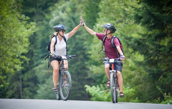 Felice coppia cavalcare su una strada asfaltata di montagna in bicicletta — Foto Stock