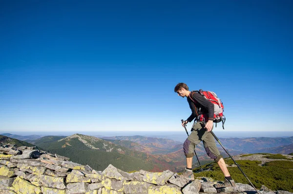 Homem mochileiro andando no cume rochoso da montanha — Fotografia de Stock