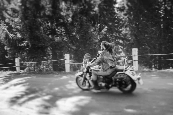 Байкер едет на своем мотоцикле по дороге в лесу — стоковое фото