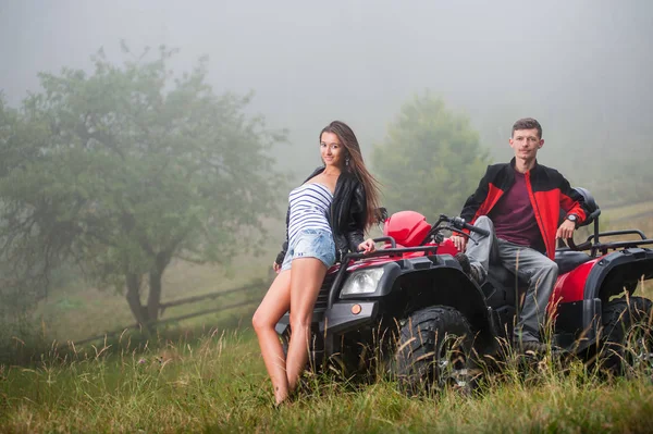 Coppia felice vicino a quattro ruote ATV nella natura nebbiosa — Foto Stock