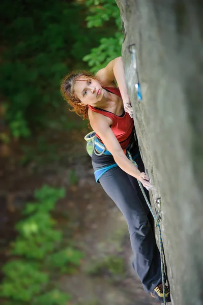 Beautiful woman climber climbing steep rock with rope — Stock Photo, Image