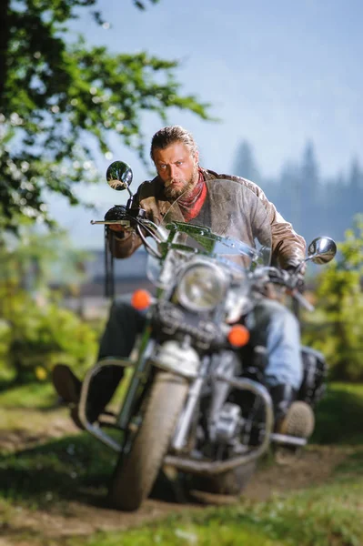 Biker driving his cruiser motorcycle on road in the forest — Stock Photo, Image