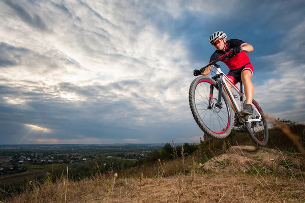 Ciclista de montaña montando donwhill contra el cielo azul de la noche — Foto de Stock