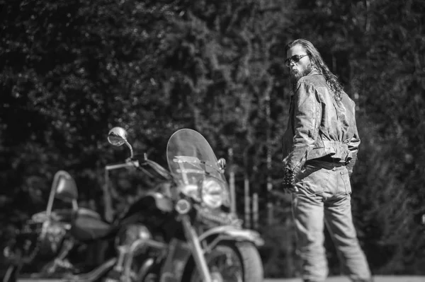 handsome biker standing by his custom made cruiser motorcycle