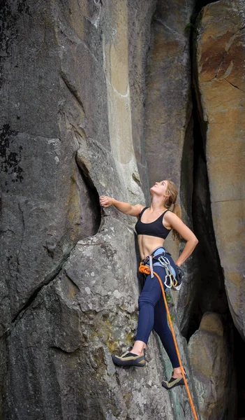 Mulher alpinista escalada com corda em uma parede rochosa — Fotografia de Stock