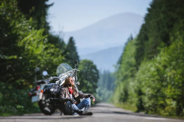 オートバイの近くの道路上に座っている男性のバイカー — ストック写真