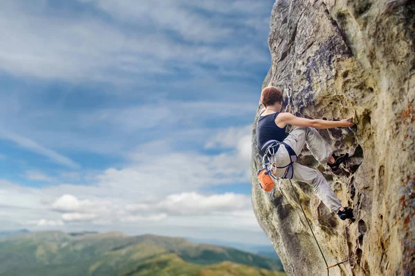 Жіночий альпініст на крутому висячому скелястому скелі — стокове фото