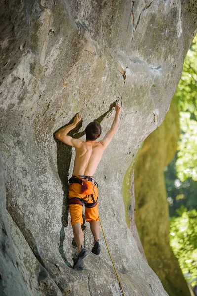 Male rock climber climbing with rope on a rocky wall — Stock Photo, Image