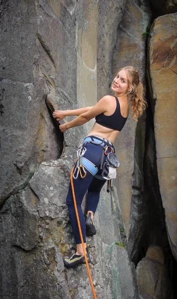 Mulher alpinista escalada com corda em uma parede rochosa — Fotografia de Stock