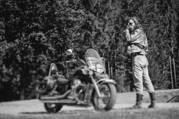 ハンサムな彼のカスタム作られた巡洋艦のバイクのそばに立ってのバイクに乗る人 — ストック写真