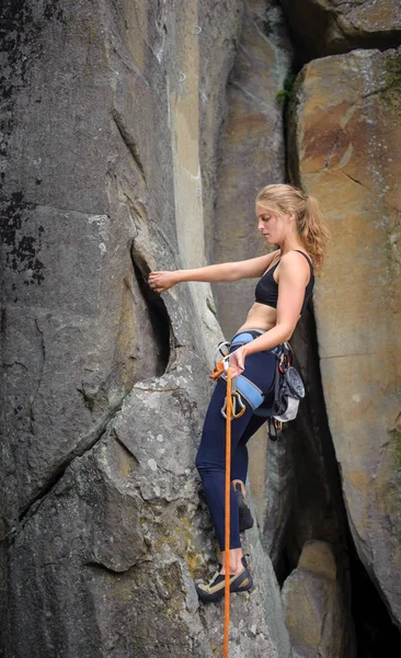 Mulher alpinista escalada com corda em uma parede rochosa — Fotografia de Stock