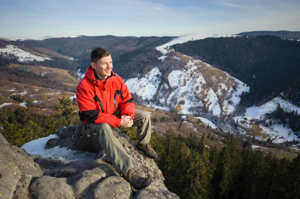 Αρσενικό τουριστικά που κάθεται σε βράχο στην κορυφή του βουνού — Φωτογραφία Αρχείου