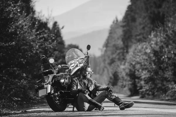 Unrasierter männlicher Biker sitzt auf Feldweg neben Motorrad — Stockfoto