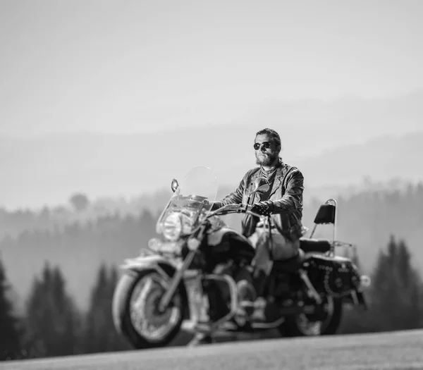 Brutal biker sitting on his motorcycle on a sunny day — Stock Photo, Image