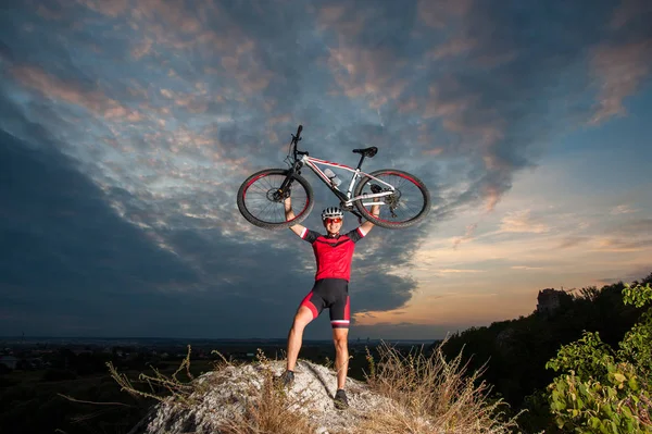 Ciclista elevando a bicicleta de montanha acima de sua cabeça com sucesso — Fotografia de Stock