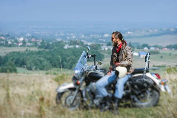 Brutal motociclista sentado em sua moto em um dia ensolarado — Fotografia de Stock