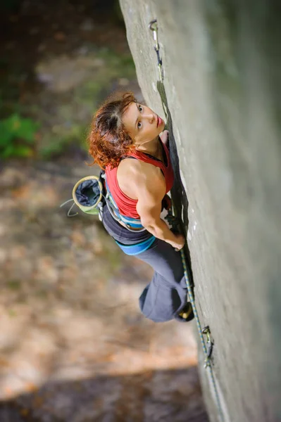 Beautiful woman climber climbing steep rock with rope — Stock Photo, Image
