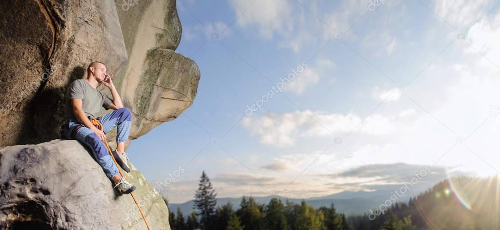 Male climber climbing big boulder in nature with rope
